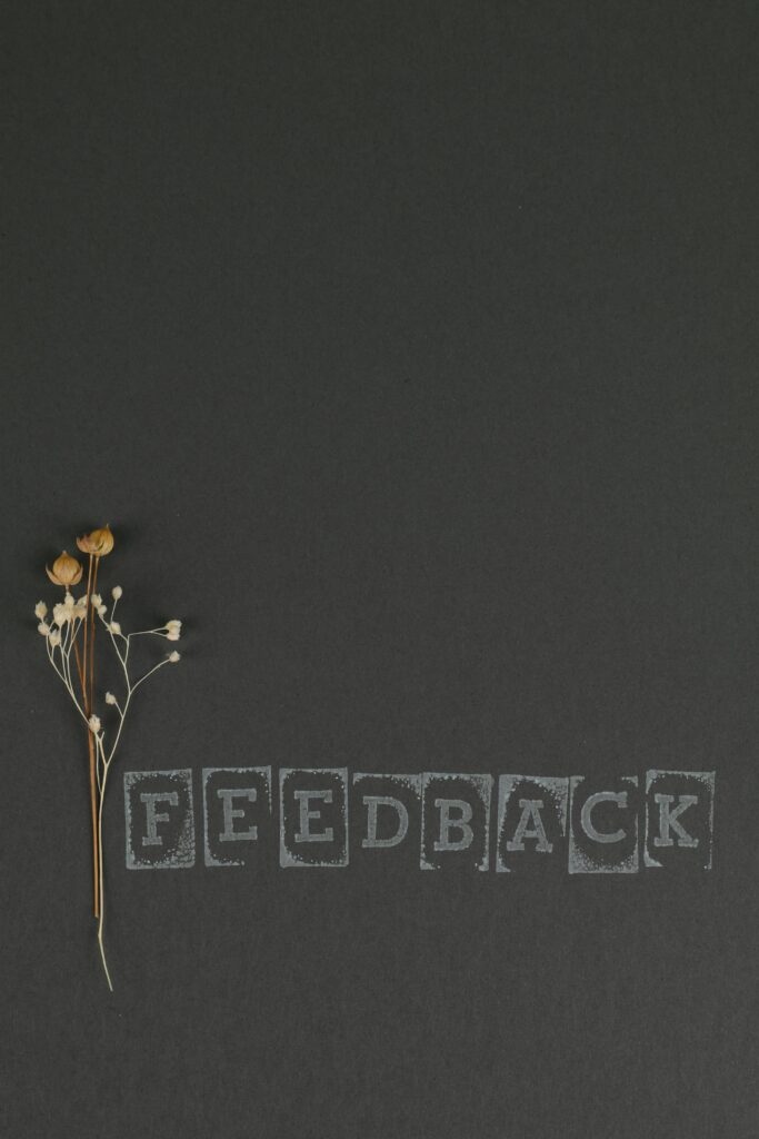 Artistic image of dried flowers on a dark surface featuring the word 'Feedback'.