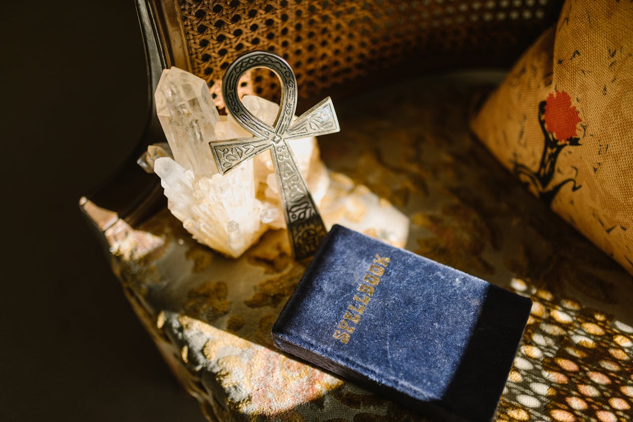 Vintage Ankh and crystals on a rustic table with sunlight casting patterns.